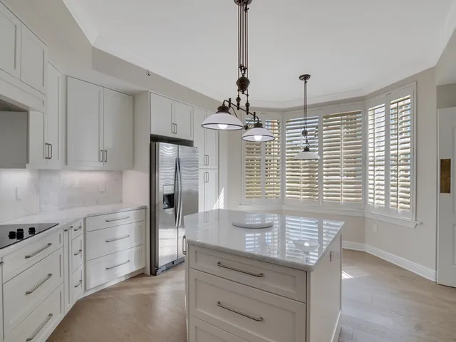 a kitchen with granite countertop white cabinets and refrigerator