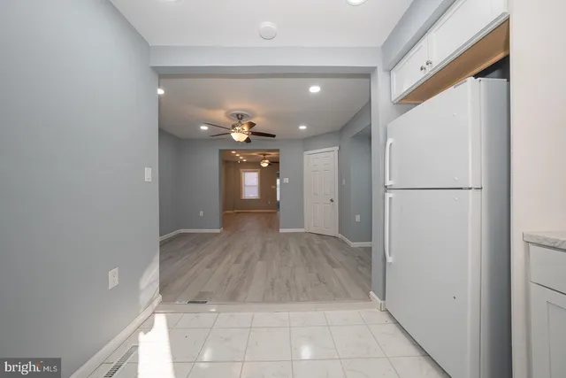 a view of a hallway with wooden floor and a refrigerator