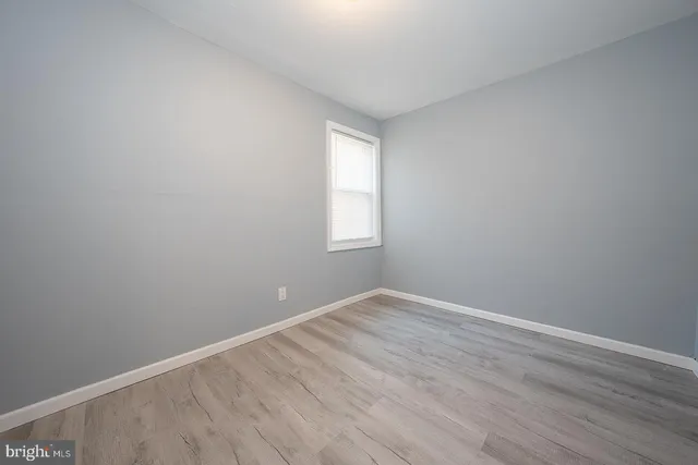 an empty room with wooden floor and window