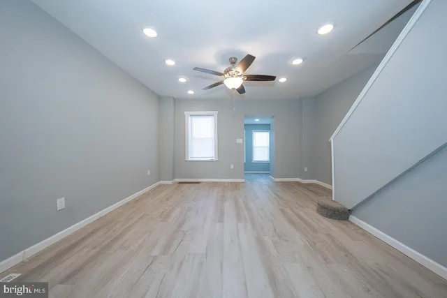 a view of empty room with wooden floor and fan