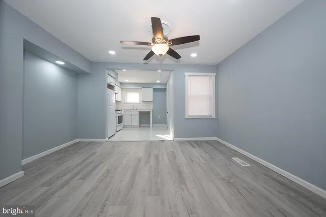 a view of empty room with wooden floor and fan