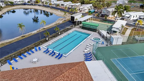 an aerial view of a tennis ground and a cars park side of the road