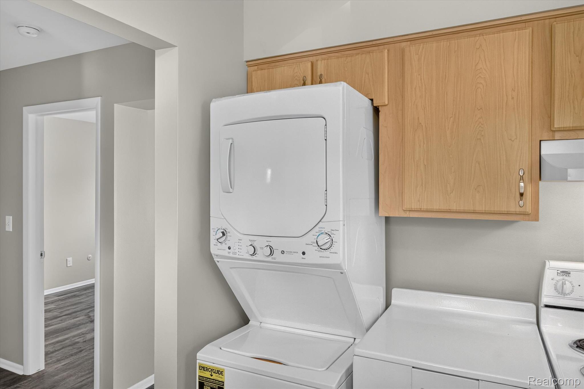 22000 Beck Road, Unit 101 Northville, MI 48167 - Photo 10 of 20 Stacked washer and dryer, wood-finish cabinetry, white countertop, and gray wall paint