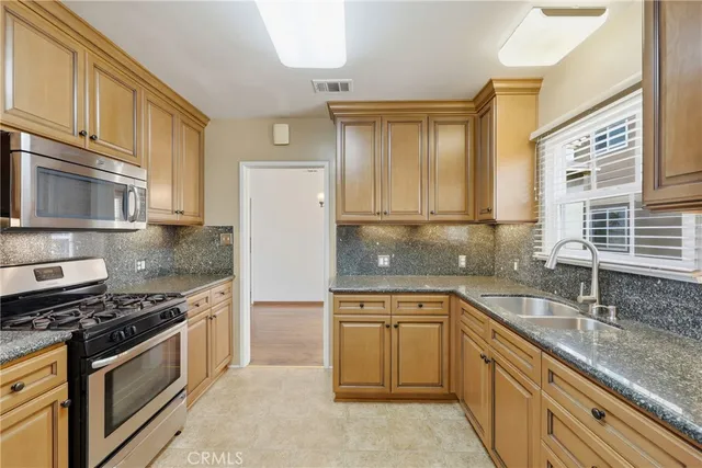a kitchen with stainless steel appliances granite countertop a sink stove and refrigerator