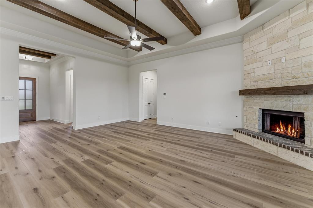 2208 Continent Court Krum, TX 76249 - Photo 14 of 26 Expansive living area featuring wood-finish flooring, a tray ceiling with exposed wood beams, and a ceiling fan