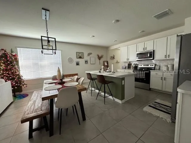 a kitchen with kitchen island a stove a sink a dining table and chairs