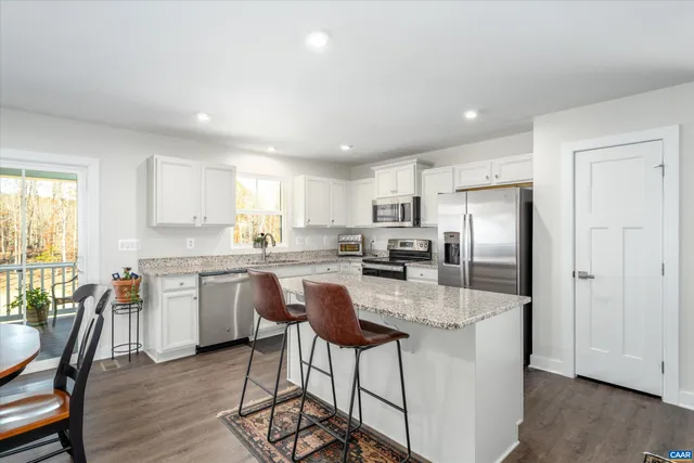a kitchen with granite countertop a center island stainless steel appliances cabinets and a window