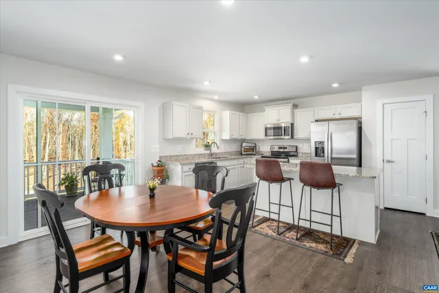 a kitchen with stainless steel appliances kitchen island granite countertop a dining table and chairs