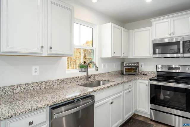 a kitchen with granite countertop white cabinets and a stove top oven
