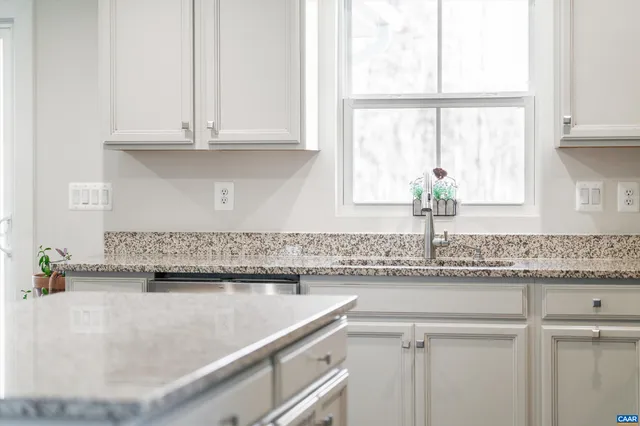 a kitchen with granite countertop white cabinets and a window