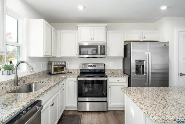 a kitchen with stainless steel appliances granite countertop a stove sink and refrigerator