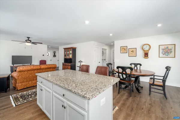 a living room with stainless steel appliances granite countertop furniture and wooden floor