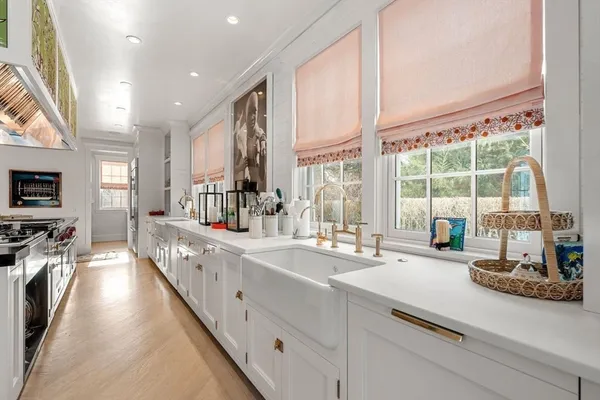 a large white kitchen with sink and large window