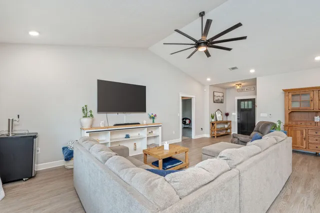 a living room with furniture kitchen view and a wooden floor