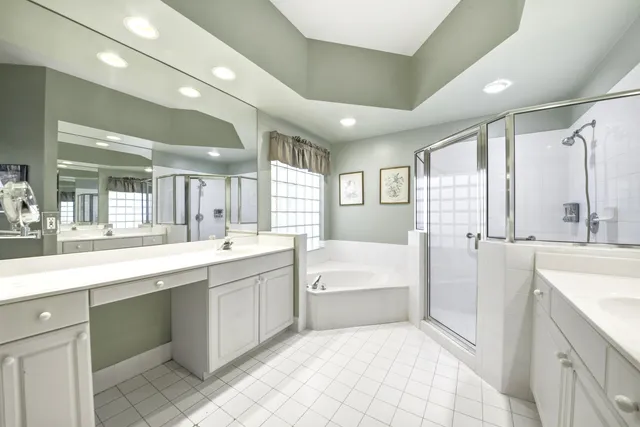a large white bathroom with a large tub sink shower and mirror