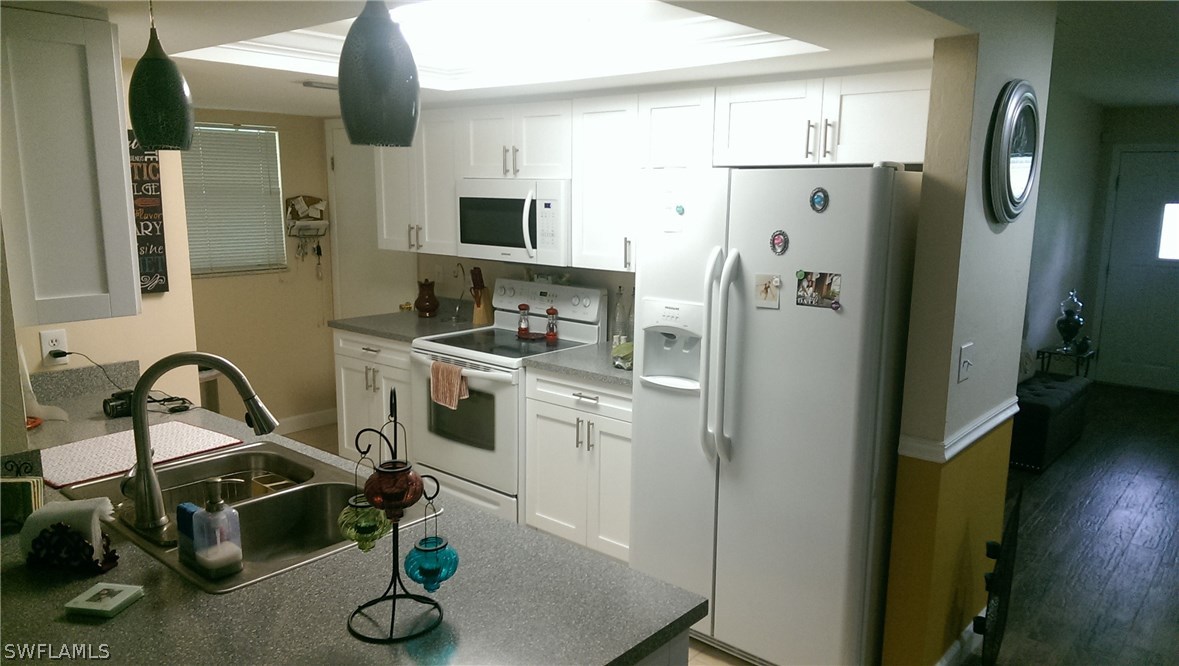 317 Maine Road Lehigh Acres, FL 33936 - Photo 3 of 5 a kitchen with stainless steel appliances a refrigerator a sink a stove and white cabinets