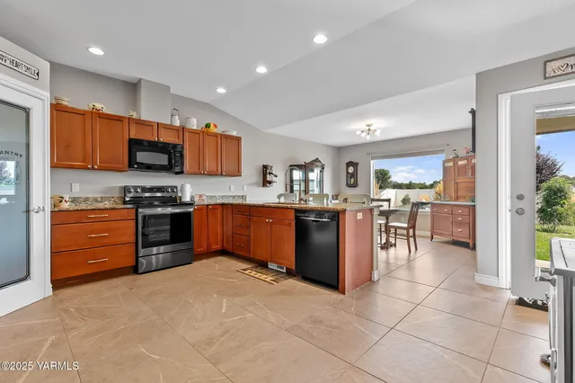 a kitchen with stainless steel appliances granite countertop a stove top oven a sink a dining table and chairs