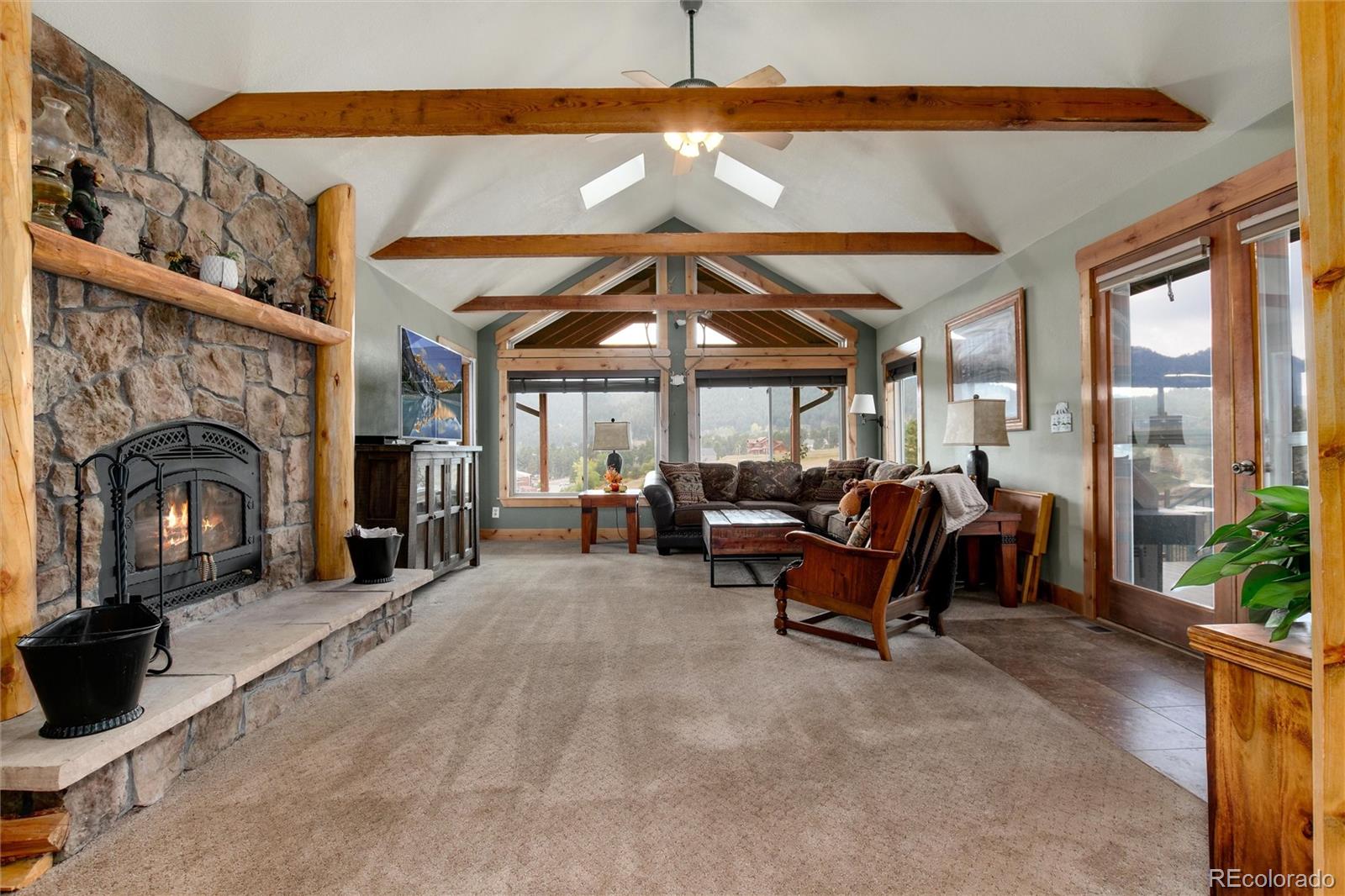 23724 Moqui Road Indian Hills, CO 80454 - Photo 16 of 39 a living room with furniture a fireplace and a floor to ceiling window