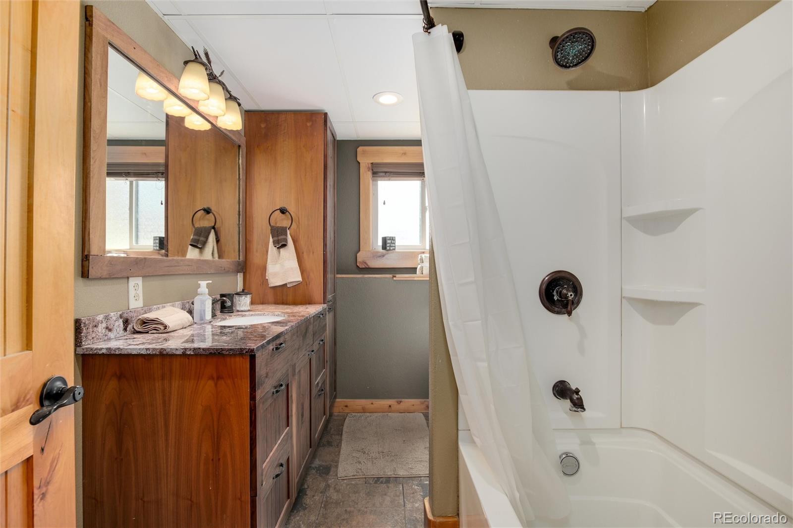 23724 Moqui Road Indian Hills, CO 80454 - Photo 21 of 39 a bathroom with a granite countertop sink a mirror and a bathtub