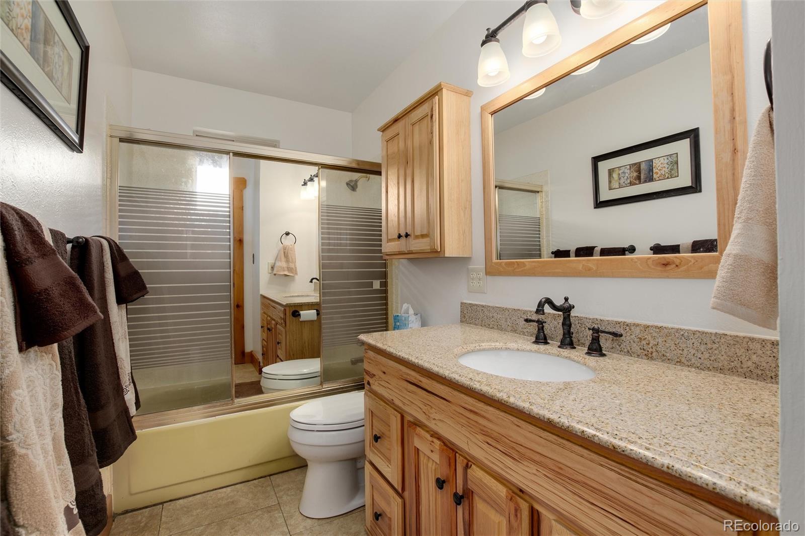 23724 Moqui Road Indian Hills, CO 80454 - Photo 27 of 39 a bathroom with a granite countertop sink toilet and shower