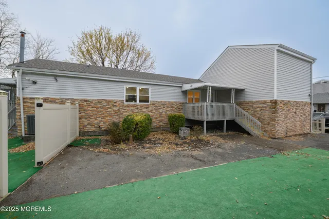 a view of a house with a yard and lawn chairs with wooden fence