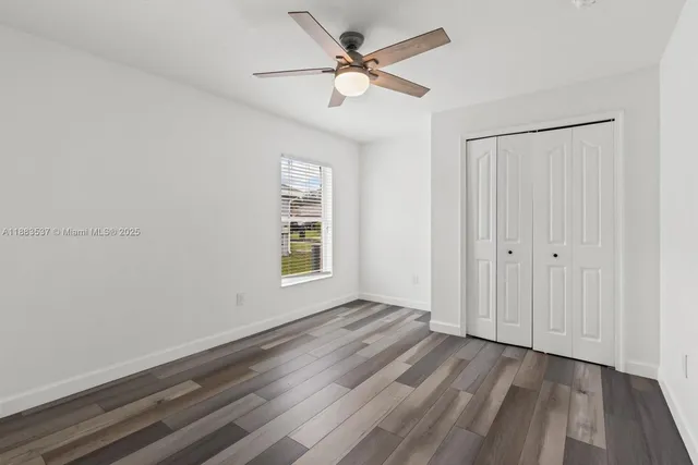 an empty room with wooden floor and ceiling fan