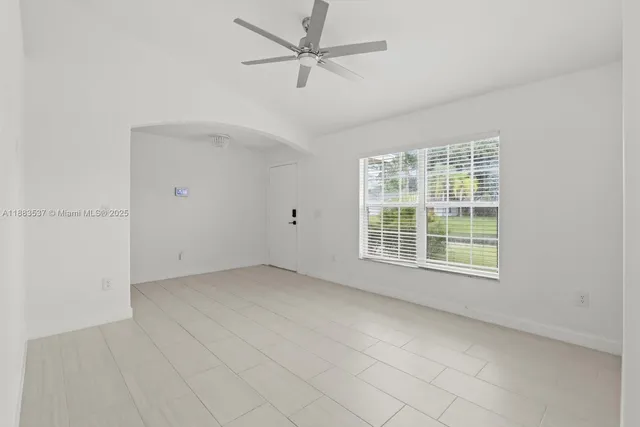 an empty room with chandelier fan and windows