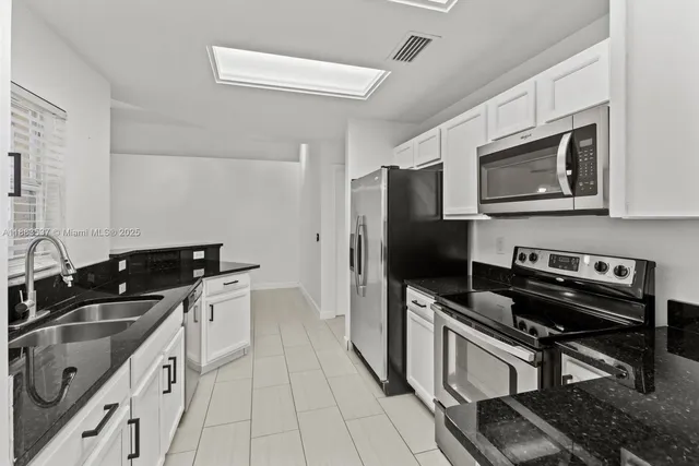 a kitchen with stainless steel appliances granite countertop a sink a refrigerator and a granite counter tops