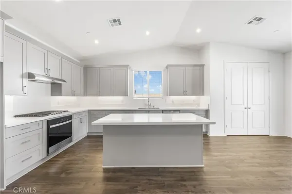 a kitchen with kitchen island sink stove and white cabinets