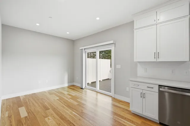 a view of a kitchen with white cabinets and wooden floor