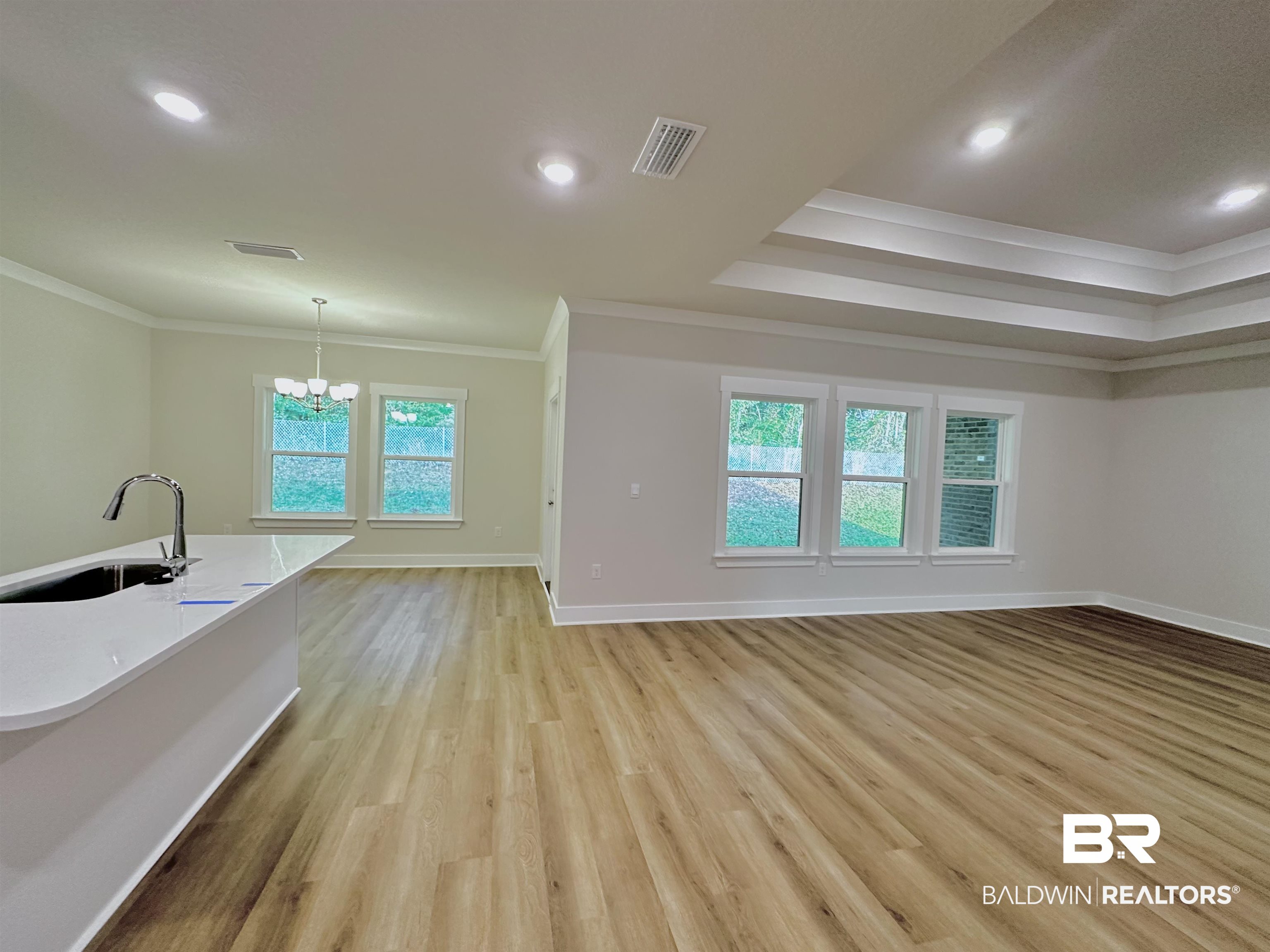 342 Barndling Street Fairhope, AL 36532 - Photo 11 of 50 Unfurnished living room featuring light hardwood / wood-style floors, a notable chandelier, sink, and crown molding