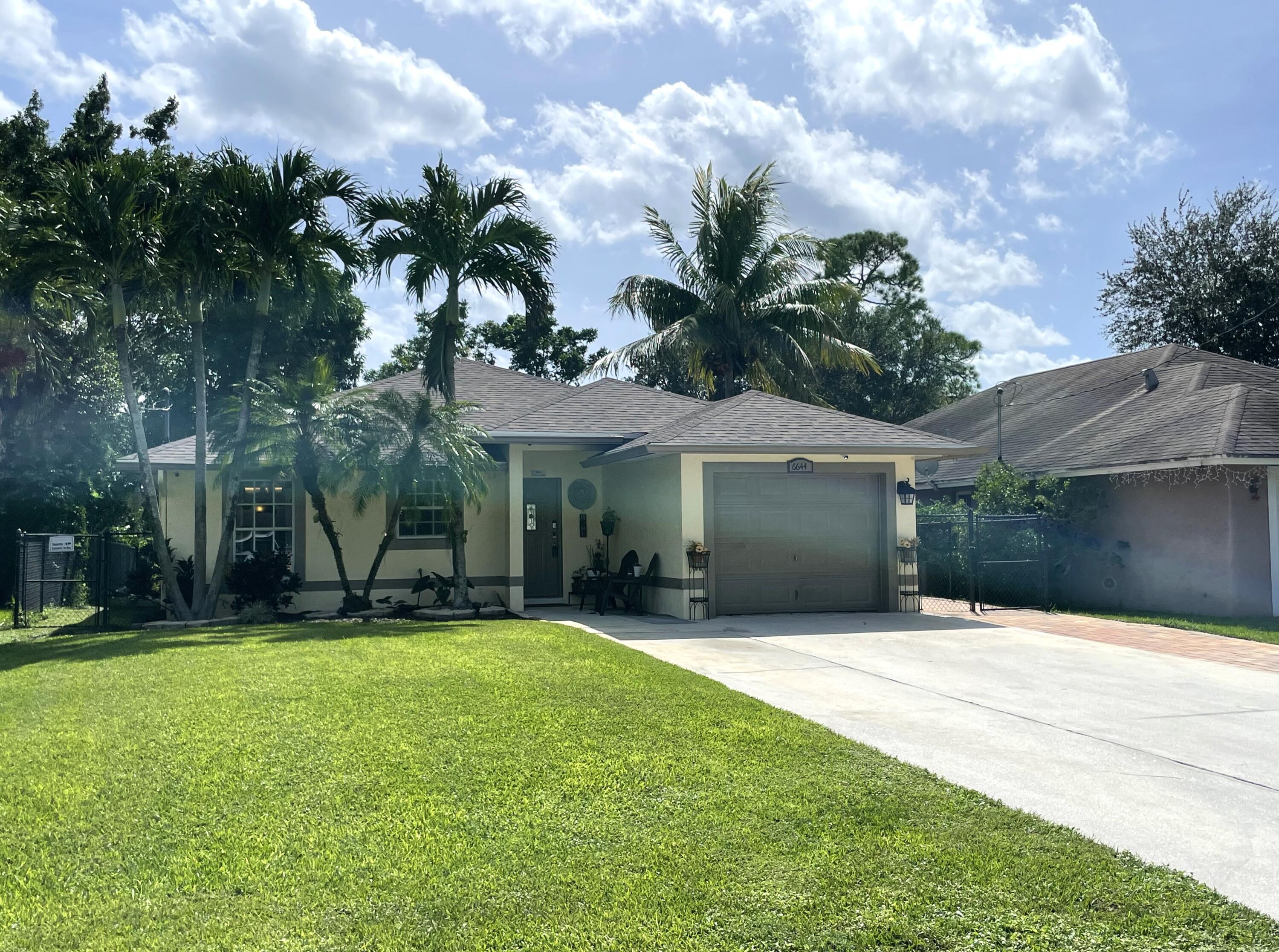 6644 4th Street Jupiter, FL 33458 - Photo 1 of 24 a front view of a house with a yard and garage
