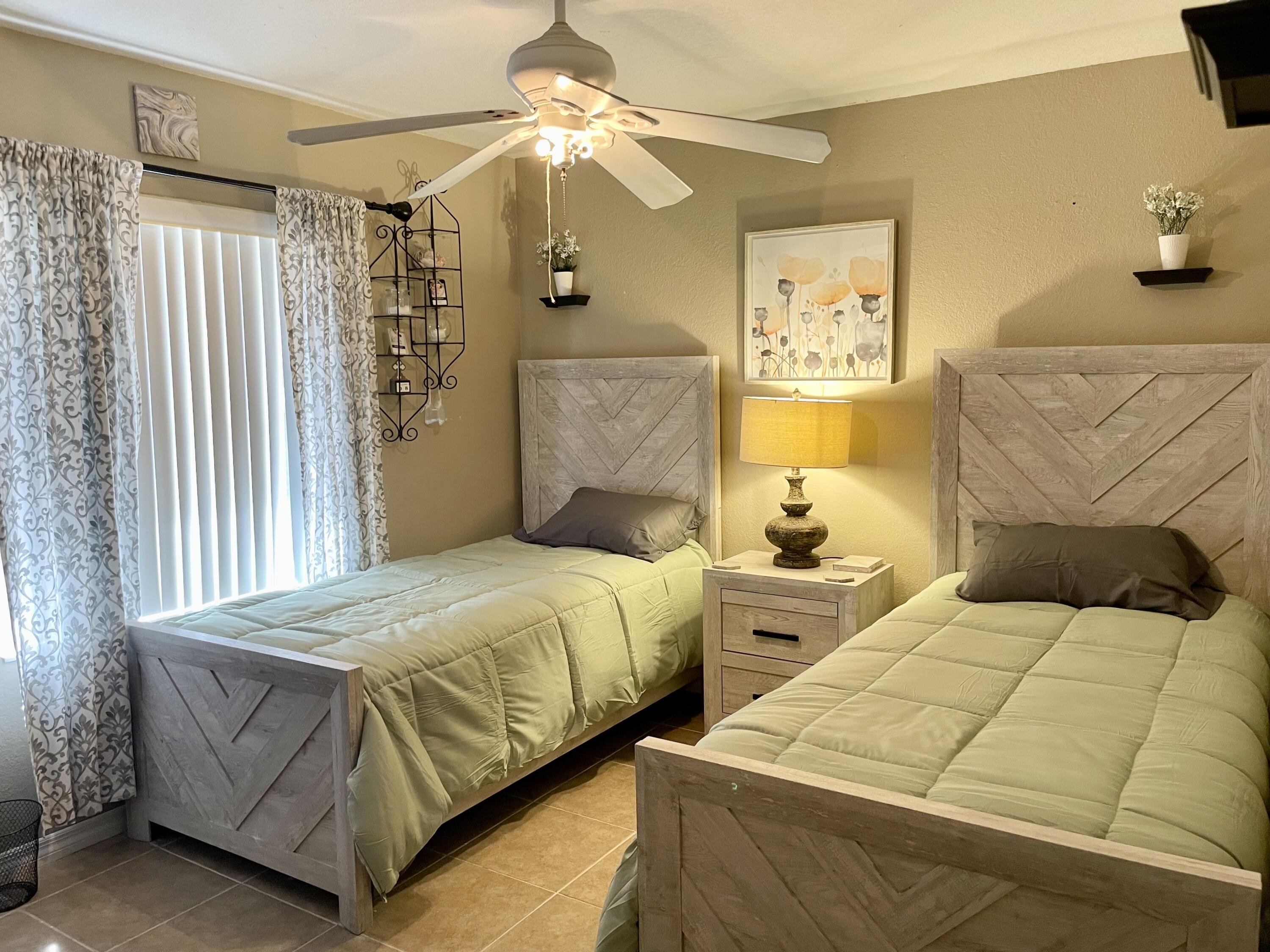 6644 4th Street Jupiter, FL 33458 - Photo 16 of 24 a bedroom with two beds and a chandelier