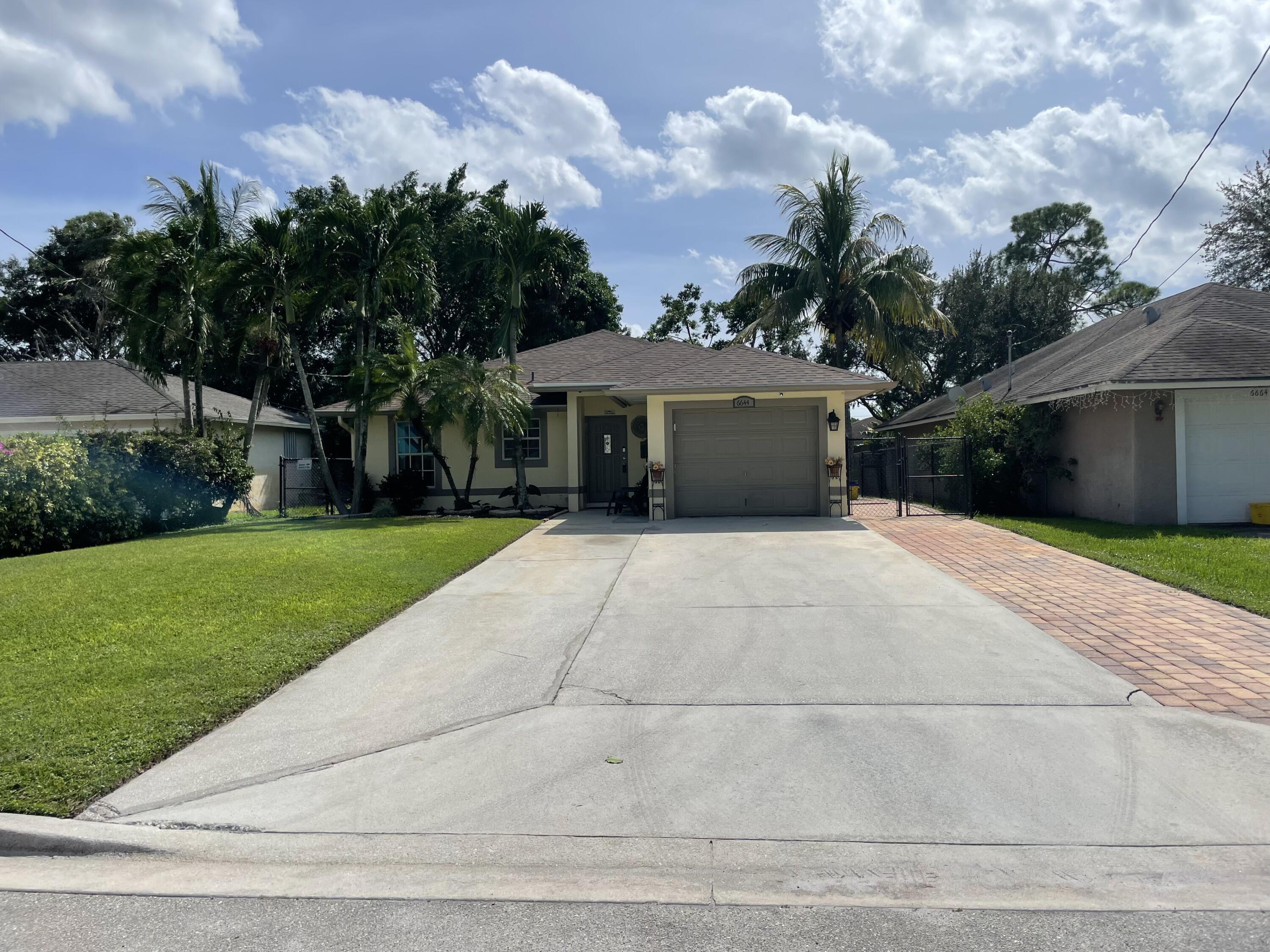 6644 4th Street Jupiter, FL 33458 - Photo 2 of 24 a front view of a house with a yard and trees