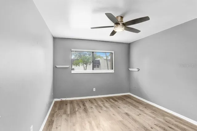 an empty room with wooden floor and ceiling fan