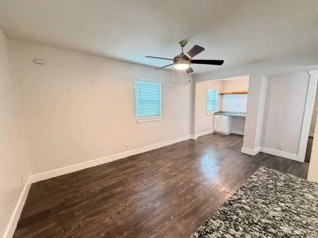 a view of an empty room with a window and wooden floor