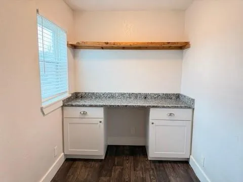 a utility room with granite countertop cabinets and wooden floor
