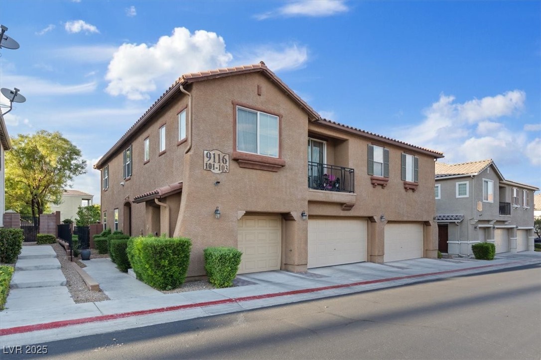 View of front facade with an attached garage, stucco siding, a balcony, and a residential view