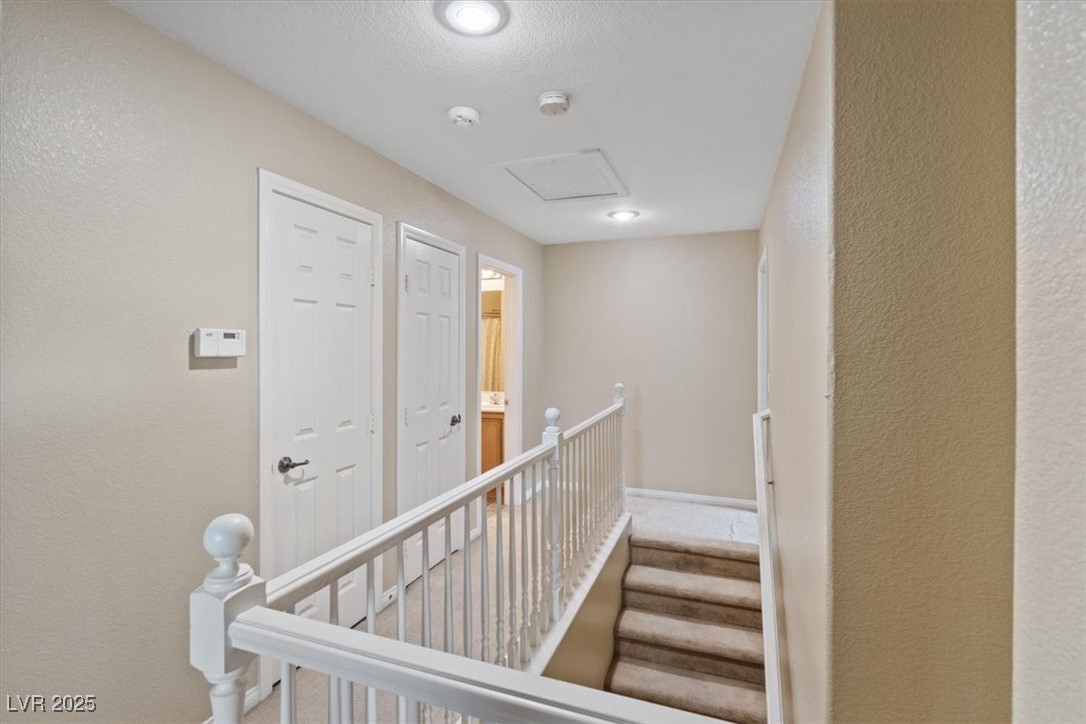 9116 Alpine Grove Avenue, Unit 103 Las Vegas, NV 89149 - Photo 12 of 30 Hall with a textured wall, an upstairs landing, and carpet flooring