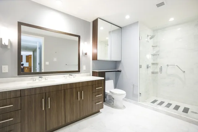 a bathroom with a sink a toilet a large mirror and shower