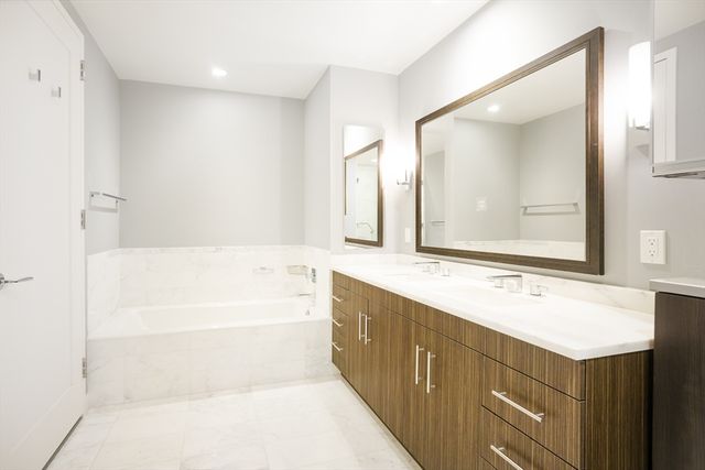 a bathroom with a bathtub sink vanity and mirror