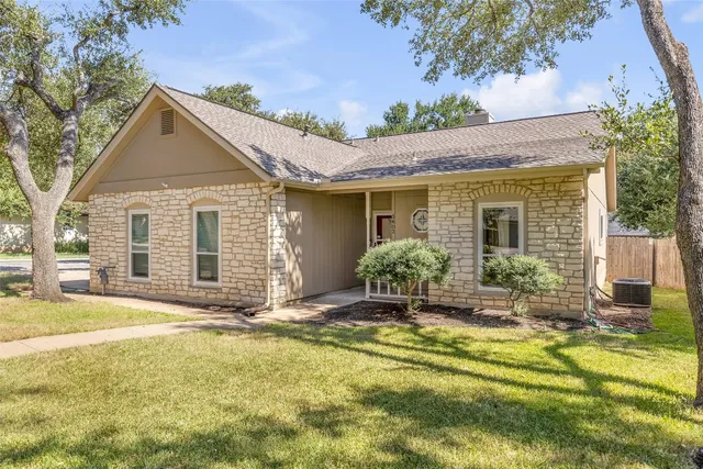 a front view of house with yard and trees in the background