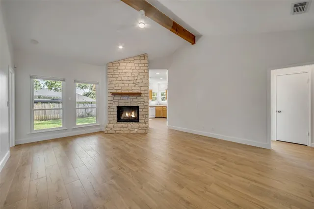 an empty room with wooden floor a fireplace and windows