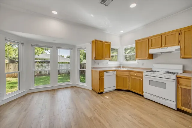 a kitchen with stainless steel appliances wooden floors and white cabinets