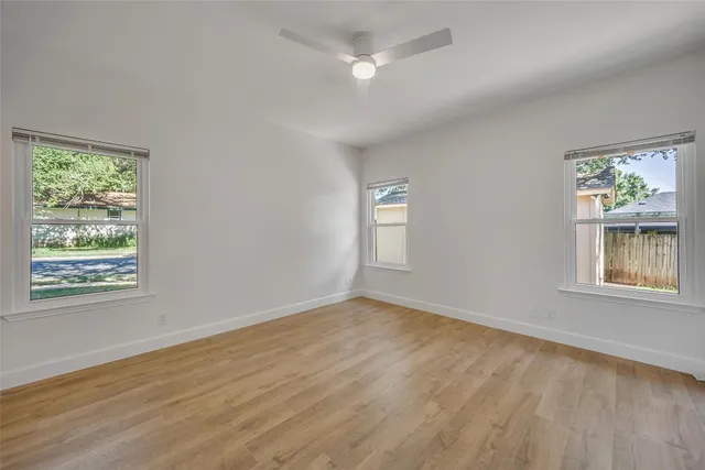 a view of an empty room with a window and wooden floor