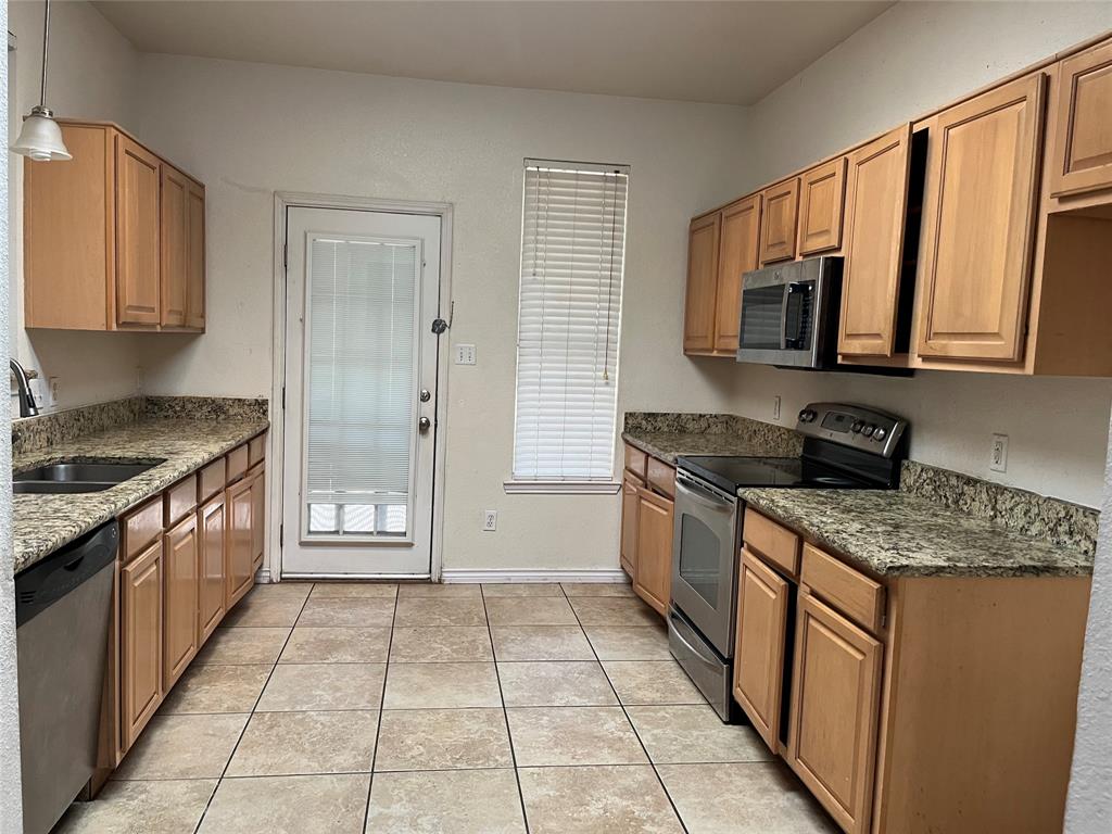 8712 Rainy Lake Drive Fort Worth, TX 76244 - Photo 5 of 13 Kitchen with stainless steel appliances, dark stone countertops, light tile patterned flooring, and pendant lighting