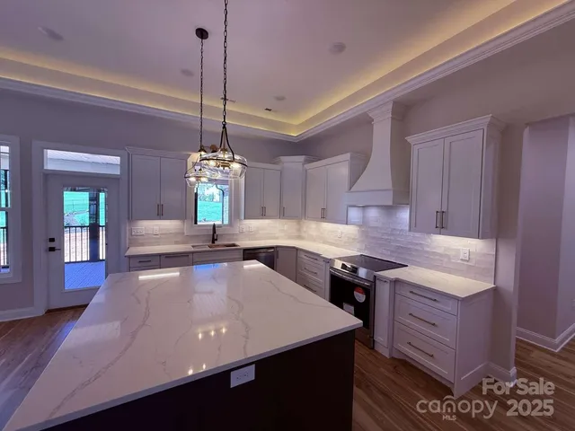 a kitchen with kitchen island granite countertop stove top oven a sink dishwasher and a wooden cabinets