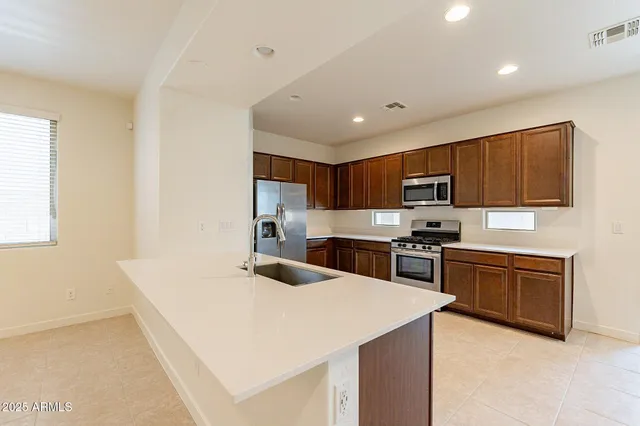 a kitchen with stainless steel appliances kitchen island granite countertop a stove sink and cabinets