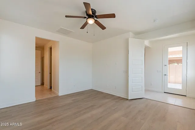 an empty room with wooden floor ceiling fan and windows