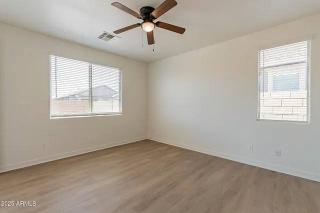 a view of empty room with wooden floor and fan